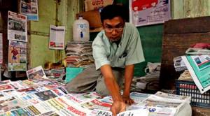 A man arranges local newspapers fronting photos of U.S. President Barack Obama and Myanmar's State Counsellor and Foreign Minister Aung San Suu Kyi at his roadside shop, Thursday, Sept. 15, 2016, in Yangon, Myanmar. Myanmar economists and businessmen welcome President Barack Obama’s announcement that the U.S. will lift economic sanctions and restore long-lost trade benefits to the Southeast Asian country. (AP Photo/Thein Zaw)