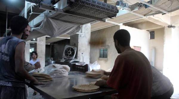 In this photo taken Oct. 1, 2016 and provided by the local council of Aleppo city, Syrians bakers make bread at a bakery, in Aleppo, Syria. The opposition-held districts of the Syrian city have been surrounded and under siege for months. Russian and Syrian warplanes are bombing the streets into rubble and government forces are chipping away at the pocket of opposition control. (Local Council of Aleppo City via AP)