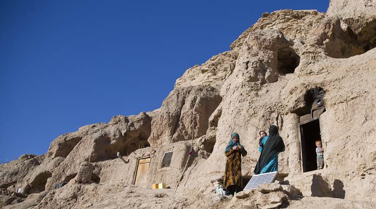 In this Monday, Nov. 7, 2016 photo, Marzia, 30, in blue, talks to her neighbor near her cave in Bamiyan, Afghanistan. Marzia and her husband Qadeer thought themselves lucky when they moved into a 1,700-year-old Buddhist cave hand-carved into the side of a mountain in Afghanistan's central highlands _ it was clean and dry, warm in the winter, cool in the summer, and there was plenty of work on the local farms. (AP Photos/Massoud Hossaini)