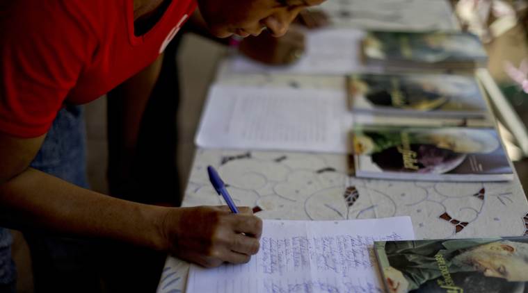 A man signs the, "solemn oath to carry out the concept of the revolutionary" as expressed by the late leader Fidel Castro, at the President Salvador Allende School, in Havana, Cuba, Monday, Nov. 28, 2016. Cubans on Monday began bidding farewell to Castro, the man who ruled the island for nearly half a century. Cuba's government has declared nine days of national mourning following Castro's death Friday night at age 90. (AP Photo/Natacha Pisarenko)