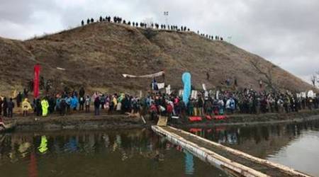 In this photo provided by Nancy Trevino, protesters against the Dakota Access oil pipeline gather at and around a hill, referred to as Turtle Island, where demonstrators claim burial sites are located, Thursday, Nov. 24, 2016 in Cannon Ball, N.D. The hill is across a body of water from where hundreds and times thousands of people have camped out for months to protest the construction of the four-state pipeline. (Nancy Trevino via AP)