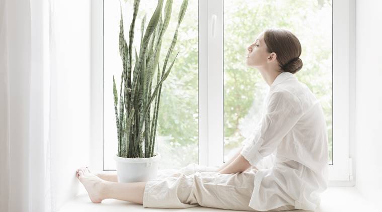 Woman sitting on windowsill with flower