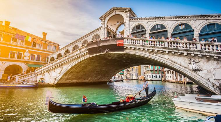 Beautiful view of traditional Gondola on famous Canal Grande with Rialto Bridge at sunset in Venice, Italy with retro vintage Instagram style filter and lens flare effect.