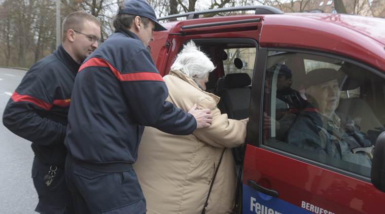 Rescuers help a woman into a car of the fure brigade after she left her home in Augsburg, Germany, Sunday, Dec. 25, 2016. Thousands of people in the German town of Augsburg have temporarily left Christmas presents and decorations behind while authorities disarm a World War II bomb. The bomb was uncovered last week during construction work. (Stefan Puchner/dpa via AP)