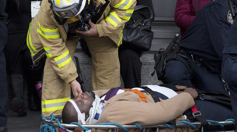 An injured passenger is assisted by an EMS worker as he lies on a gurney outside Atlantic Terminal after a Long Island Rail Road incident, Wednesday, Jan. 4, 2017, in the Brooklyn borough of New York. Officials said a commuter train either hit something or derailed as it arrived at the terminal. (AP Photo/Mark Lennihan)