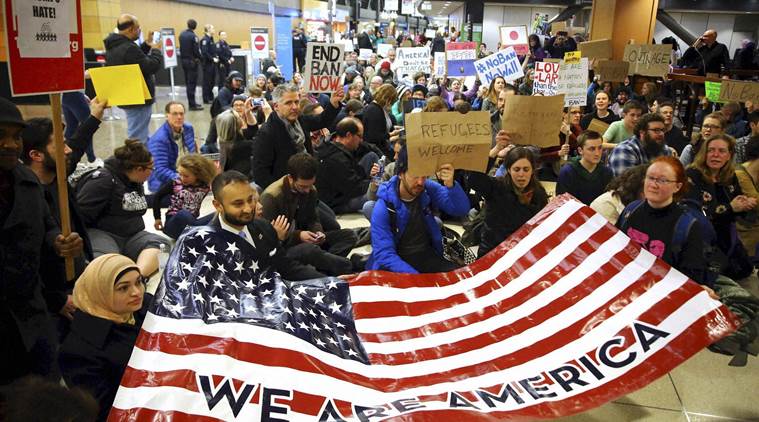 Seattle : Demonstrators sit down in the concourse and hold a sign that reads "We are America," as more than 1,000 people gather at Seattle-Tacoma International Airport, to protest President Donald Trump's order that restricts immigration to the U.S., Saturday, Jan. 28, 2017, in Seattle. President Trump signed an executive order Friday that bans legal U.S. residents and visa-holders from seven Muslim-majority nations from entering the U.S. for 90 days and puts an indefinite hold on a program resettling Syrian refugees.  AP/PTI(AP1_29_2017_000018B)