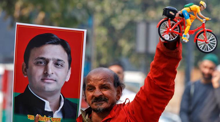 A Samajwadi (SP) party worker holds a toy bicycle representing the party's symbol and a poster of chief minister of northern state of Uttar Pradesh Akhilesh Yadav, following the Election Commission's decision to allot the bicycle symbol in Akhilesh's favour, outside the party's headquarters in Lucknow, India, January 17, 2017. REUTERS/Pawan Kumar