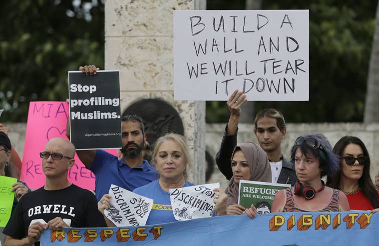 Protesters hold signs during a rally against President Donald Trump's executive order on Muslim immigration, Thursday, Jan. 26, 2017, in downtown Miami. The protesters manifested their opposition to Trump's executive order restricting immigration from some Middle Eastern and African countries. (AP Photo/Alan Diaz)