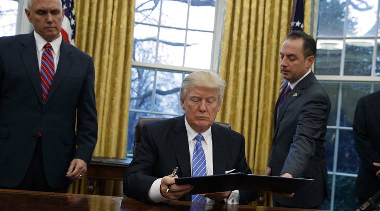 Vice President Mike Pence watches at left as White House Chief of Staff Reince Priebus hands an executive order to withdraw the U.S. from the 12-nation Trans-Pacific Partnership trade pact to President Donald Trump, Monday, Jan. 23, 2017, in the Oval Office of the White House in Washington. (AP Photo/Evan Vucci)