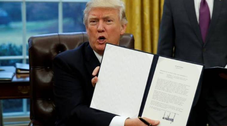 President Donald Trump holds up the executive order on withdrawal from the Trans Pacific Partnership after signing it in the Oval Office of the White House in Washington January 23, 2017. REUTERS/Kevin Lamarque