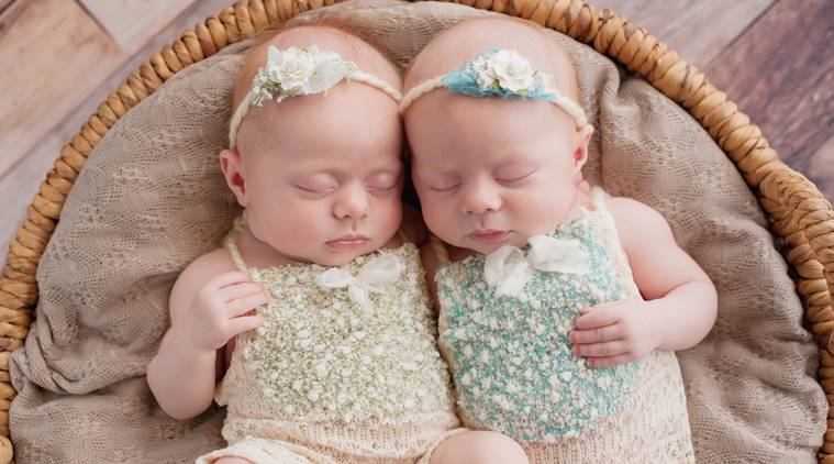 Seven week old fraternal, twin baby girls sleeping in a wicker basket. Shot in the studio on a rustic wood background.