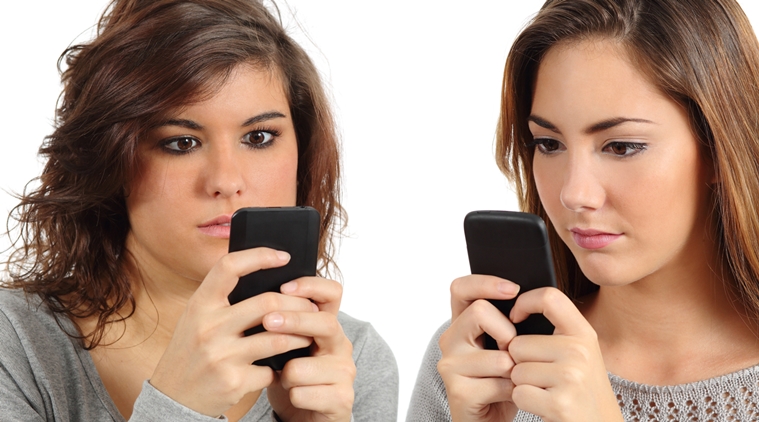 Two teenagers addicted to the smart phone technology isolated on a white background