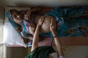 "Suman, a 25-year-old pregnant woman, lies on an examination table as a nurse places her hands on her stomach during a check up at a community health centre in the remote village of Chharchh, in the central Indian state of Madhya Pradesh, February 24, 2012." *** Local Caption *** "Suman, a 25-year-old pregnant woman, lies on an examination table as a nurse places her hands on her stomach during a check up at a community health centre in the remote village of Chharchh, in the central Indian state of Madhya Pradesh, February 24, 2012. In rural Madhya Pradesh, an innovative free maternity ambulance service called ""Janani Express"", which runs in partnership between the state government and the United Nations Children's Fund (UNICEF), is trying to increase the number of babies born in clinics where proper care can be provided to the mothers and newborn children, and infant mortality can be decreased. Before this initiative, women would have been left to give birth in the fields or on mud floors. Now, the free ambulance brings pregnant women across dusty roads to health clinics where they can give birth safely under basic medical supervision, be nursed afterwards and educated on the importance of breastfeeding and hygiene before returning to their villages and communities. The United Nations' International Women's Day will be celebrated on March 8. Picture taken February 24, 2012. REUTERS/Vivek Prakash (INDIA - Tags: HEALTH SOCIETY POVERTY)"