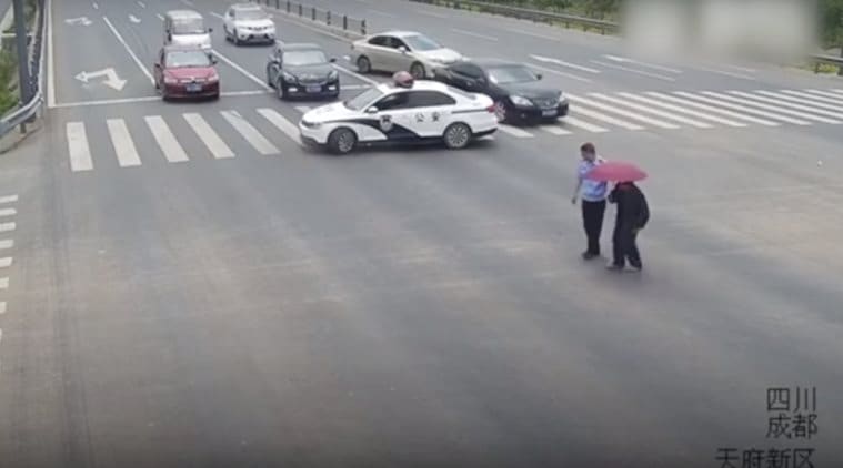 chinese policeman helps old man viral video, chinese policeman stops traffic to help old man, chinese policeman stops traffic to help old man cross viral video, indian express, indian express news