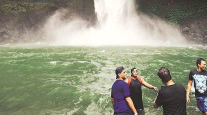 Young men cool themselves off in a waterfall as temperatures