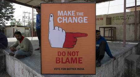 People sit around a sign at a polling station in Dharmsala, India, Thursday, Nov. 9, 2017. Results for elections in this northern Indian state of Himachal Pradesh will be declared on Dec. 18. (Source: AP Photo)