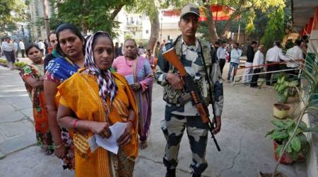 A Border Security Force (BSF) soldier stands guard as women wait to cast their votes at a polling station during the last phase of Gujarat state assembly election on the outskirts of Ahmedabad, India, December 14, 2017. REUTERS/Amit Dave