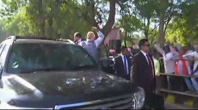 Prime Minister Narendra Modi waves to crowd gathered on his way from the airport in Ahmedabad