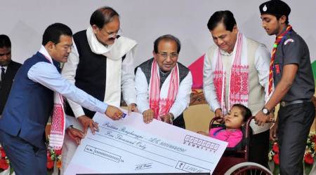 Guwahati: Vice-president M Venkaiah Naidu with Assam Governor Jagadish Mukhi and CM Sarbananda Sonowal giving away financial assistance to a 'divyang' during the inaugural ceremony of Deen Dayal Divyangjan Sahajya Achoni, on the occasion of international day for the disabled persons, at Sorusajai Stadium in Guwahati on Sunday. PTI Photo  (PTI12_3_2017_000114A)