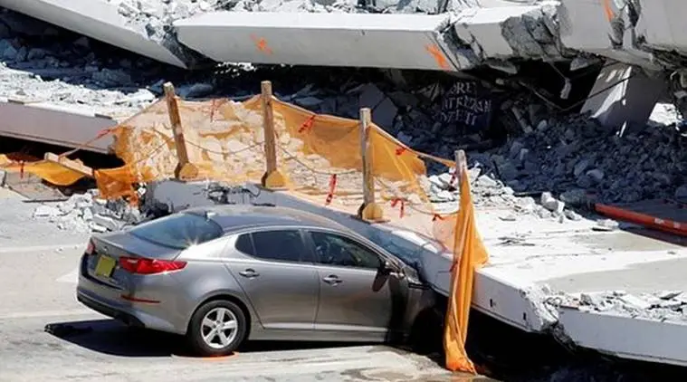 A damaged car is seen partially trapped as workers remove debris from a collapsed pedestrian bridge at Florida International University in Miami. (Reuters)
