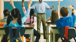 Teacher Standing in Front of a Class of Raised Hands teaching singing maths tables, a teacher making maths table songs, maths table songs