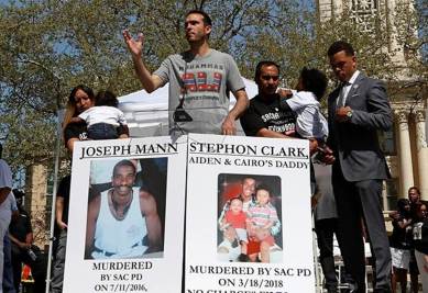 Salena Manni (L), fiancee of Stephon Clark, holds their son Cairo and an unidentified man holds son Aiden (2nd R) while Basim Elkarra speaks and Rev Shane Harris listens at a rally in Sacramento. (Reuters)