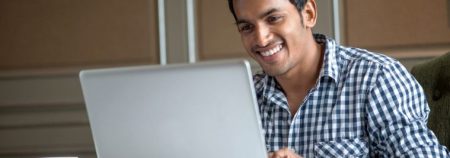 Attractive Indian Man looking at the laptop smiling
