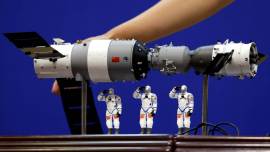 FILE PHOTO: A model of the Tiangong-1 space lab module, the Shenzhou-9 manned spacecraft and three Chinese astronauts is displayed during a news conference