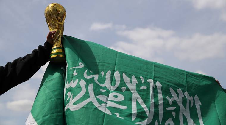 A Saudi Arabia fan holds a replica world cup outside the stadium before the match