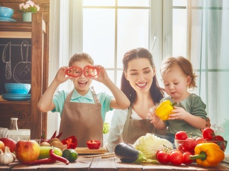 Healthy food at home. Happy family in the kitchen. Mother and children daughters are preparing the vegetables and fruit.
