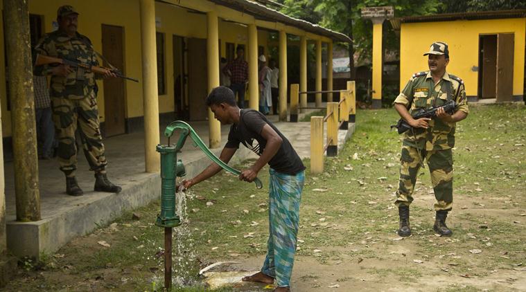 Security men stand guard as Muslim man uses hand pump to drink water after arriving to check if his name is included in the NRC draft in Bur Gaon village, 70 kilometers (44 miles) east of Guwahati, on Monday. (AP)