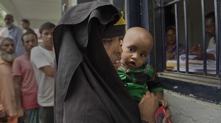 A Muslim woman holding her child checks if their names are included in the NRC list, in Mayoung, about 55 kilometers (34 miles) east of Guwahati, on Monday. (PTI)