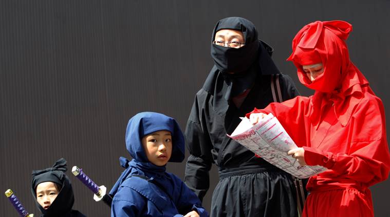A family dressed as ninjas look at a map as they search for hidden ninja mannequins during a ninja festival in Iga