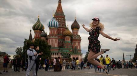 FILE - In this Tuesday, July 3, 2018 file photo a woman jumps as she poses for a photograph at the Red Square during the 2018 soccer World Cup in Moscow, Russia. (AP Photo/Francisco Seco, File)
