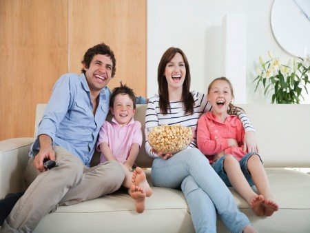 Laughing family watching TV on sofa