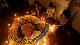 Children light candles beside a painting commemorating South African revolutionary Nelson Mandela's 100th birth anniversary at an art school in Mumbai on Wednesday. (Reuters)