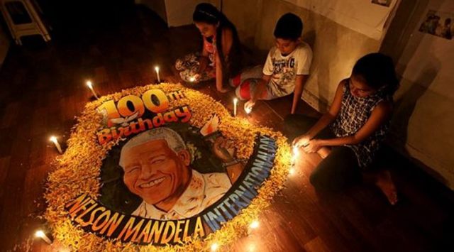 Children light candles beside a painting commemorating South African revolutionary Nelson Mandela's 100th birth anniversary at an art school in Mumbai on Wednesday. (Reuters)