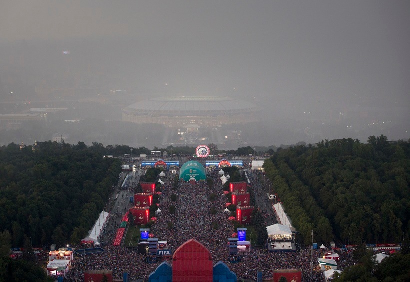 Soccer fans celebrate under a heavy rain in the fan zone near the Luzhniki stadium after the final match between France and Croatia at the 2018 soccer World Cup