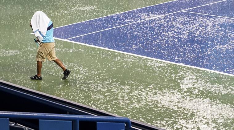 A court attendant moves toward shelter after play was suspended due to rain at the Western & Southern Open tennis tournament Thursday, Aug. 16, 2018, in Mason, Ohio