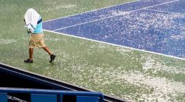 A court attendant moves toward shelter after play was suspended due to rain at the Western & Southern Open tennis tournament Thursday, Aug. 16, 2018, in Mason, Ohio