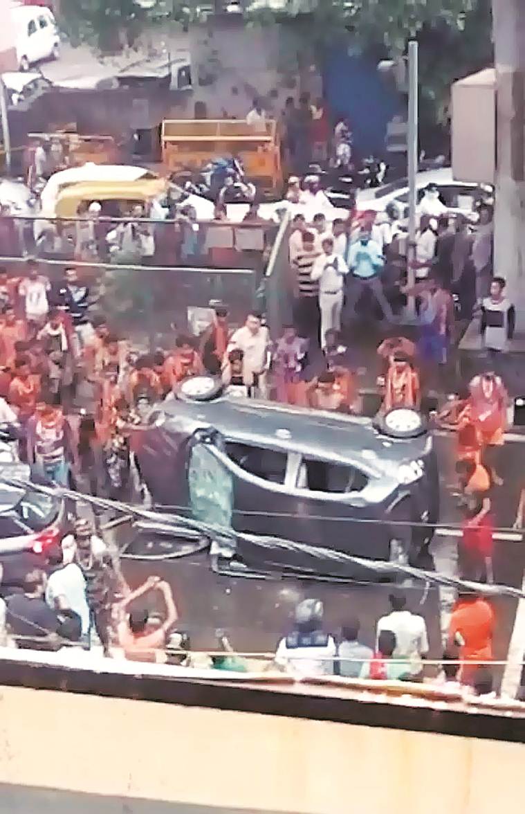 Kanwarias in Delhi. (Express photo by Praveen Khanna) It took more than 25 minutes for a dozen-odd kanwarias armed with baseball bats to overturn a Santro car, assault one of the occupants and bring traffic to a standstill — as three Police Control Room (PCR) officers tried to reason with them. But with their efforts in vain, and police realising the situation could escalate, Moti Nagar police station, barely 100 metres away, rushed five more officers to the spot — without riot gear. By the time they reached, the group, which had gone on a rampage after the Santro allegedly brushed past one of them, had disappeared. A day later, the men seem to be in the wind — and police at a loss for answers. While an FIR has been registered, it is only against "unknown persons". This, despite the incident being caught on video. According to an officer, the fact that thousands of kanwarias took the route on Tuesday has made it difficult for police to narrow down the group. For now, police said they are contacting rest shelters along the route for information about the accused. An officer said they are looking at the CCTV footage to pull out photographs that can be used to identify the men. “Of course it will be difficult to ascertain their identity. But we are confident of tracing them,” said Deputy Commissioner of Police (West) Vijay Singh. “During inquiry conducted by an ACP-rank officer, it came to the notice that one of the kanwarias was slapped by the woman, which further agitated them.” In fact, the kanwarias were not supposed to be on this stretch in the first place. But with the dedicated corridor meant for their movement waterlogged, the men took an alternative route, police said. “We had made a special corridor for them to pass through. But due to heavy rain, the makeshift route had been filled with water and they were forced to walk on the main road,” Singh said. On Wednesday, barricades had come up to ensure kanwarias had a dedicated path. Eyewitnesses have claimed that it took police over 20 minutes to send back-up to help the three PCR staffers who first reached the spot, though police maintain it was about 10 minutes. "The kanwarias started smashing the windows of the car with their bare hands. Some of them had blocked traffic by placing several pitchers, ostensibly filled with Ganga jal. They gathered within minutes, destroyed the car, and even took selfies as the two officers watched," claimed Abhishek Sharma, an eyewitness. Local police claimed they did not send men with riot gear as that could have escalated the situation. The occupants of the car — the woman who was driving and her friend who was roughed up — had opted not to file a complaint. This prompted police to register an FIR on their own — under IPC sections 427 (mischief causing damage to the amount of fifty rupees), 341 (punishment for wrongful restraint) and 34 (common intention). The woman behind the wheel, daughter of an Army officer, could not be contacted for a comment.