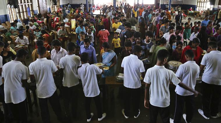 Volunteers serve food to flood affected people at a relief camp set up inside a school in Kochi. (AP)