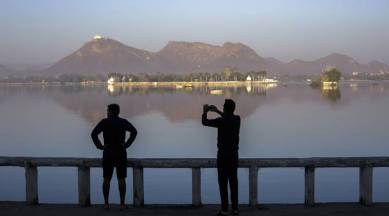 Tourists are silhouetted as they take a photograph at Fateh Sagar Lake in Udaipur, Rajasthan, India, on Saturday, Feb. 24, 2018. Photographer: Prashanth Vishwanathan/Bloomberg