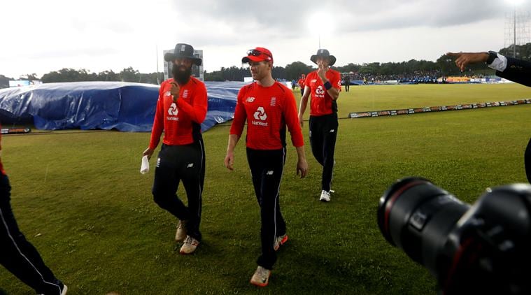 England's captain Eoin Morgan (C), Moeen Ali (L) and Olly Stone walk off the field after match was stopped due to rain