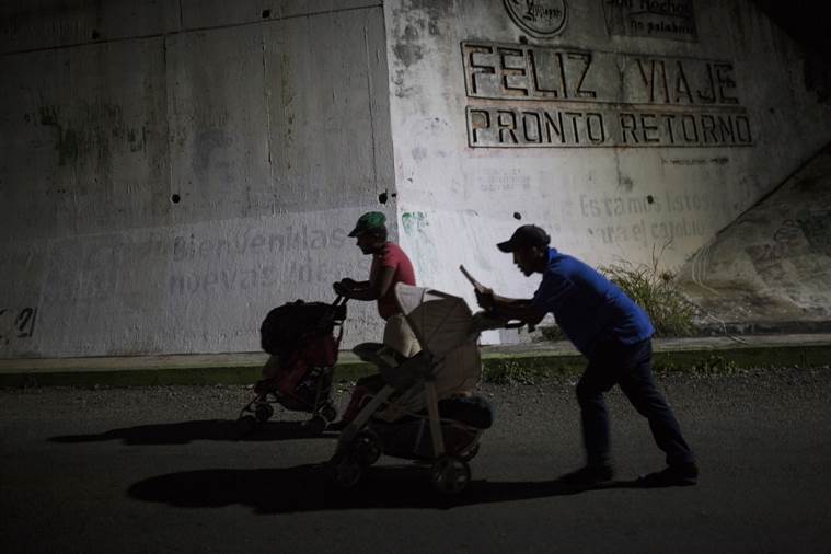 Joel Eduardo Espinar, foreground, and his wife, Yamilet Hernandez, push baby strollers as they start early in the morning towards the next town Arriaga from Pijijiapan, Mexico.