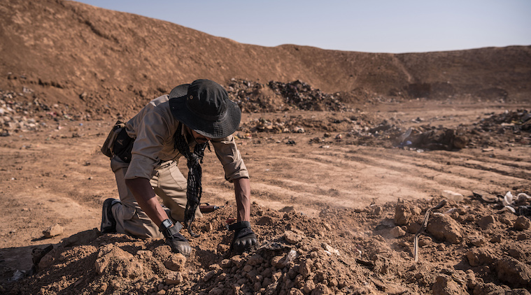 An Iraqi army soldier searches for remains at a mass grave