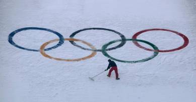 A worker grooms the snow after installing a set of Olympic Rings on the ski jump hill at the 2018 Winter Olympics at the Alpensia Ski Jumping Center in Pyeongchang, South Korea