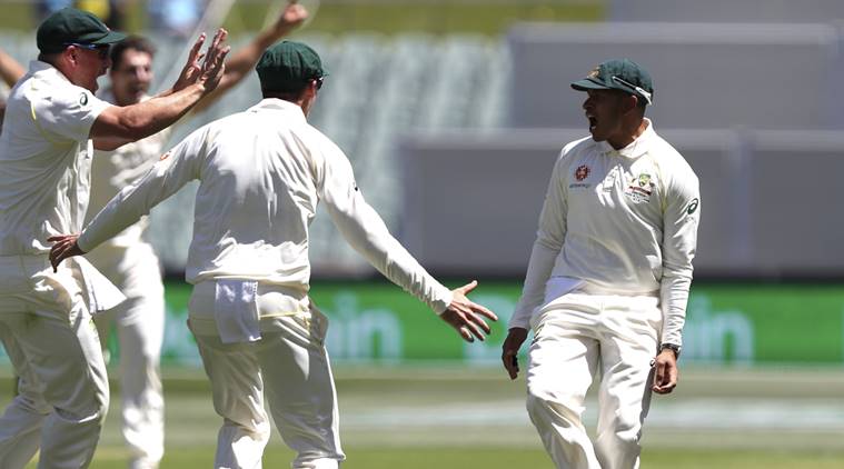 Australia's Usman Khawaja, right, celebrates with his teammates after taking a catch to dismiss India's Virat Kohli during the first cricket test between Australia and India in Adelaide