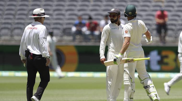 India's Virat Kohli, centre, looks to the umpire after he and opposing captain, Australia's Tim Paine came face to face after Kohli moved into Paine's path during play in the second cricket test between Australia and India in Perth, Australia