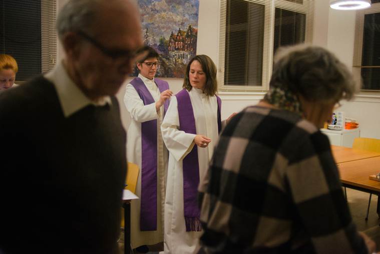 Pastors Jessa van der Vaart, center, and Rosaliene Israel, the secretary general of Protestant Church Amsterdam, don their robes before presiding over the continuous service at Bethel Church, in The Hague, Netherlands.